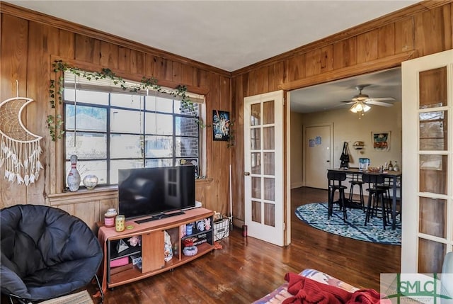 sitting room featuring dark wood-style floors, french doors, wood walls, and a ceiling fan