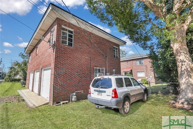 view of side of home with a yard, brick siding, and an attached garage