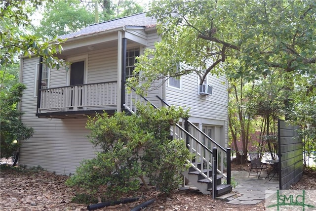 view of property exterior with a patio, a balcony, and stairs