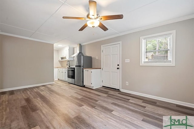 unfurnished living room featuring light wood-style floors, baseboards, and ornamental molding