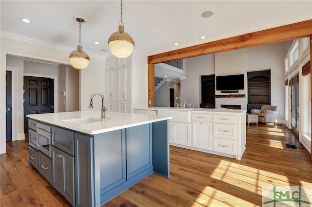 106 Commodore Dr, Savannah, GA 31410 - kitchen featuring an island with sink, a sink, light countertops, white cabinets, and light wood-style floors