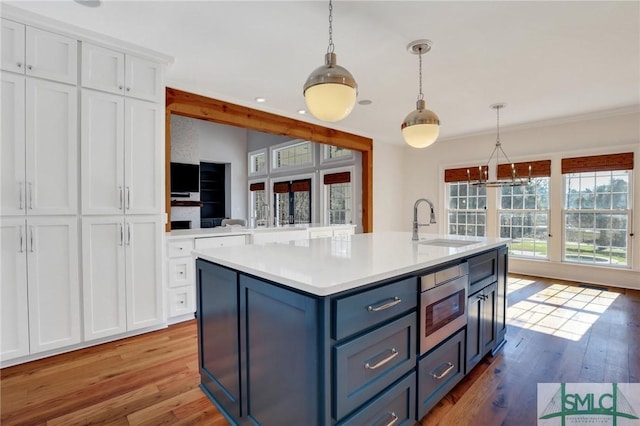 106 Commodore Dr, Savannah, GA 31410 - kitchen with a kitchen island with sink, a sink, wood finished floors, white cabinets, and light countertops