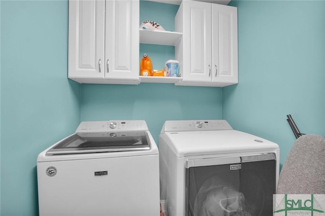 clothes washing area featuring washer and clothes dryer and cabinet space