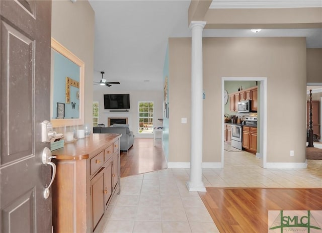 entrance foyer with ceiling fan, light tile patterned flooring, a fireplace, baseboards, and ornate columns