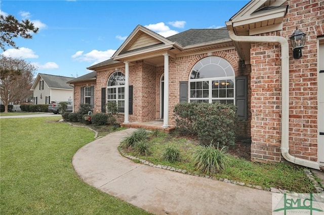 view of front of home with brick siding, a front lawn, and a shingled roof