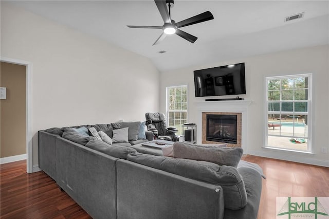 living room with vaulted ceiling, a glass covered fireplace, dark wood-style floors, and a wealth of natural light