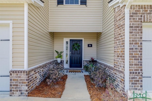 entrance to property with a garage and brick siding