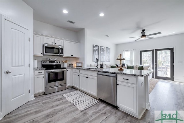 kitchen featuring visible vents, white cabinetry, stainless steel appliances, and a sink