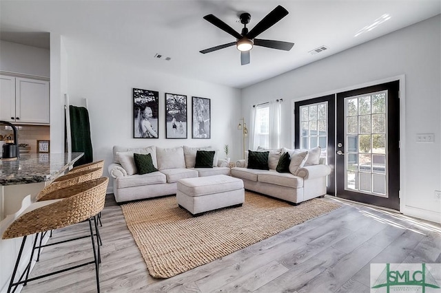 living room featuring ceiling fan, french doors, light wood-style flooring, and visible vents