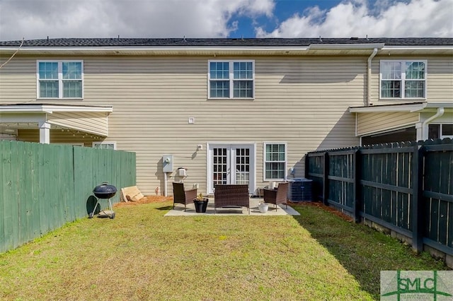 rear view of property featuring a patio, a yard, and a fenced backyard