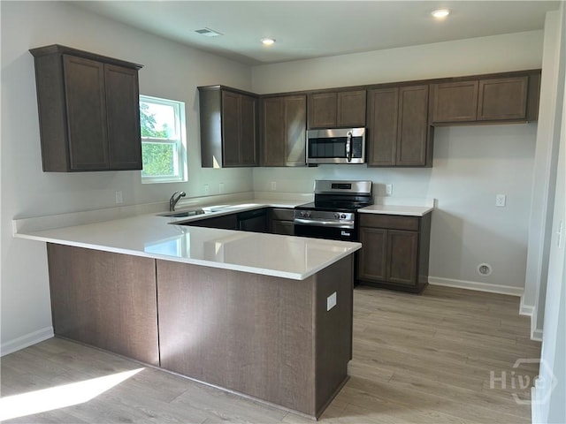108 Stillhouse Dr, Springfield, GA 31329 - kitchen with stainless steel appliances, a peninsula, light wood finished floors, dark brown cabinets, and recessed lighting