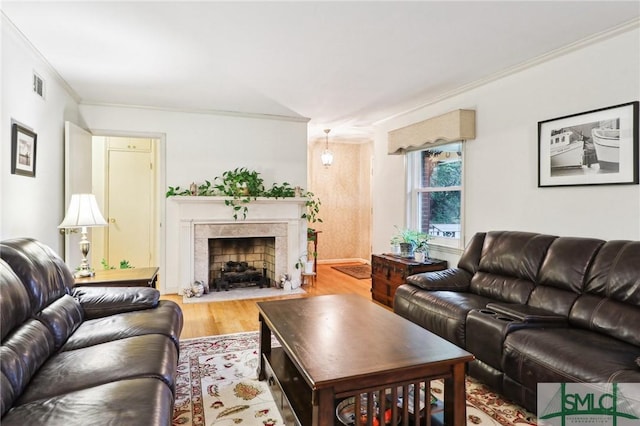 living room with a high end fireplace, visible vents, crown molding, and wood finished floors