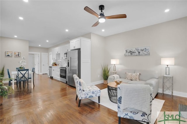living room featuring ceiling fan, baseboards, wood finished floors, and recessed lighting