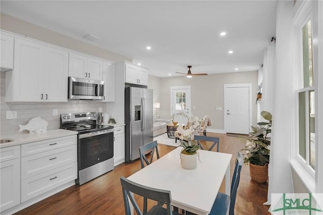 kitchen featuring stainless steel appliances, backsplash, white cabinetry, light countertops, and a ceiling fan