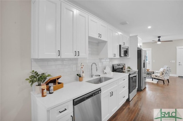 kitchen with stainless steel appliances, a sink, tasteful backsplash, light countertops, and white cabinets