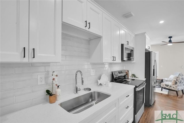 kitchen featuring appliances with stainless steel finishes, a sink, white cabinetry, and decorative backsplash
