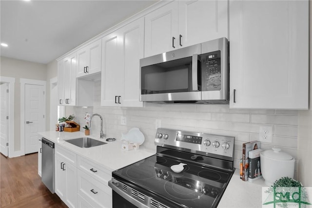 kitchen with stainless steel appliances, a sink, light countertops, and white cabinetry