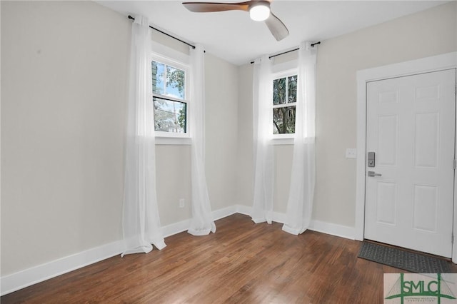 spare room with wood finished floors, a ceiling fan, and baseboards