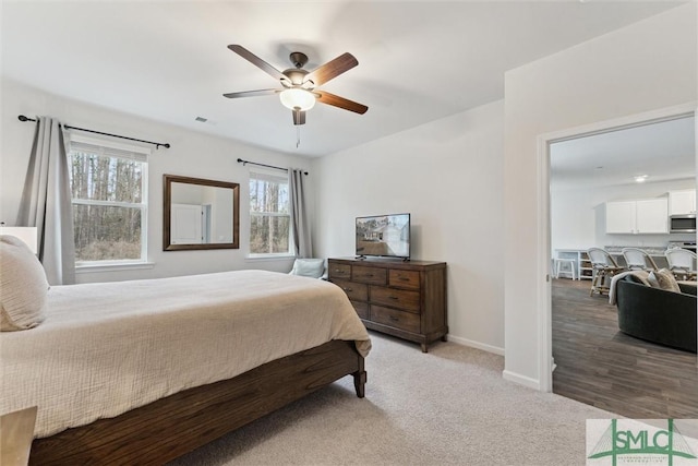 bedroom with light colored carpet, ceiling fan, visible vents, and baseboards