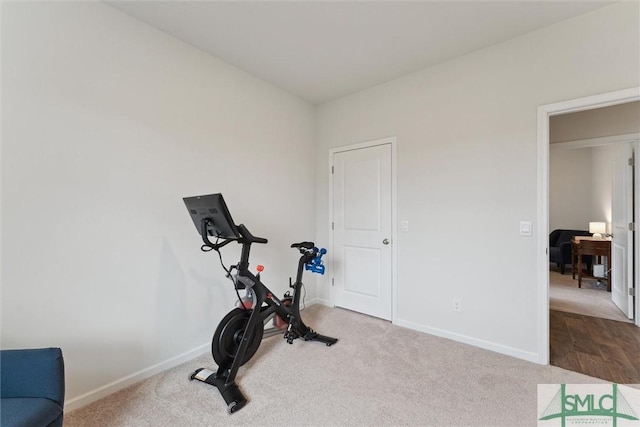 exercise area featuring light carpet and baseboards