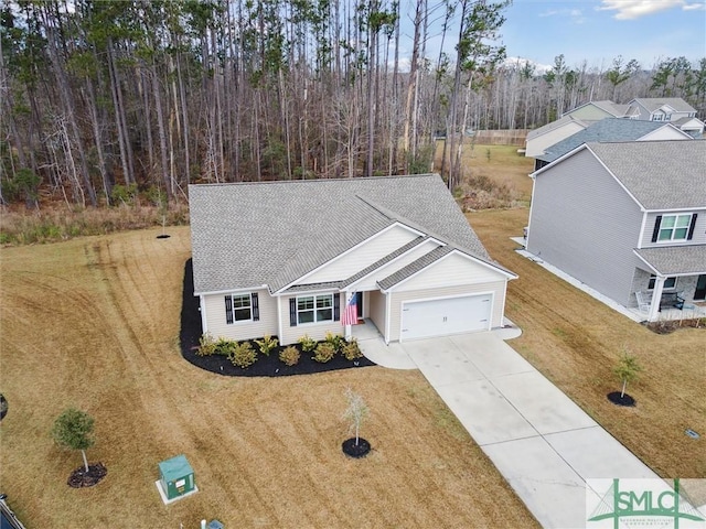 view of front of property with driveway, an attached garage, a shingled roof, and a front yard