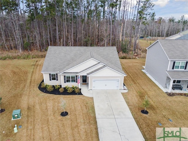 view of front facade featuring driveway, an attached garage, a shingled roof, and a front yard