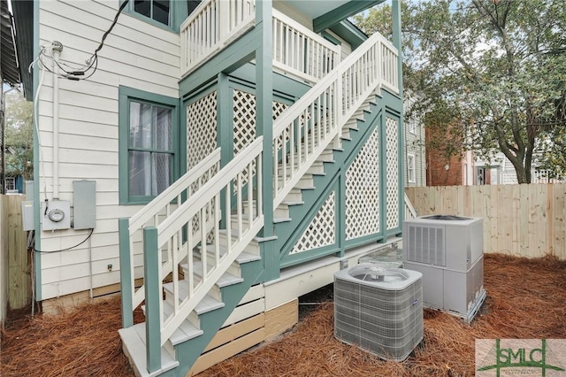 exterior space featuring central AC, fence, and stairs