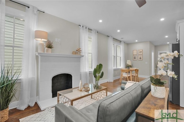 living area featuring a fireplace, baseboards, wood finished floors, and recessed lighting