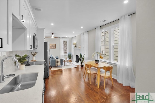 kitchen with light countertops, appliances with stainless steel finishes, a healthy amount of sunlight, white cabinetry, and a sink