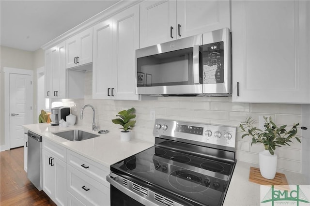 kitchen with a sink, white cabinetry, light countertops, appliances with stainless steel finishes, and backsplash