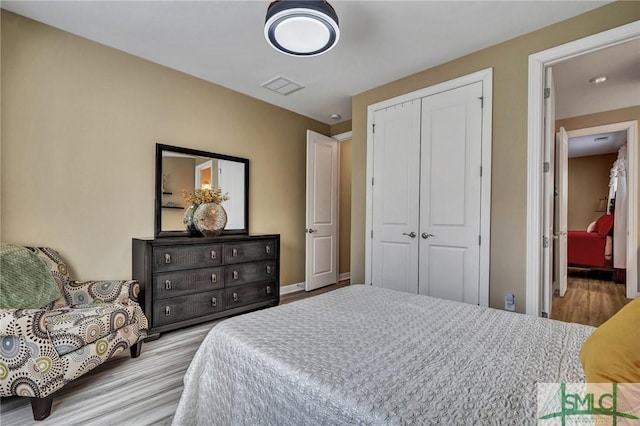 bedroom with light wood-style floors, a closet, and visible vents