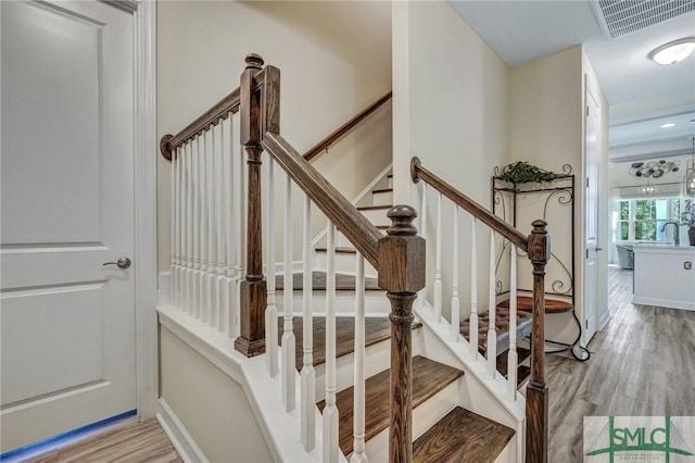 stairs with visible vents and wood finished floors