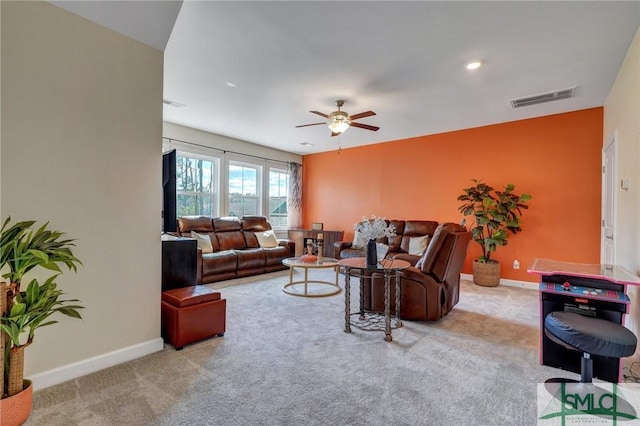 carpeted living area featuring a ceiling fan, visible vents, and baseboards