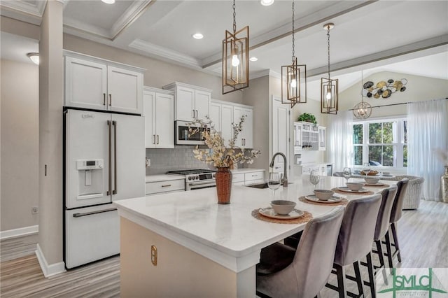 kitchen featuring white refrigerator with ice dispenser, white cabinetry, a sink, and a center island with sink