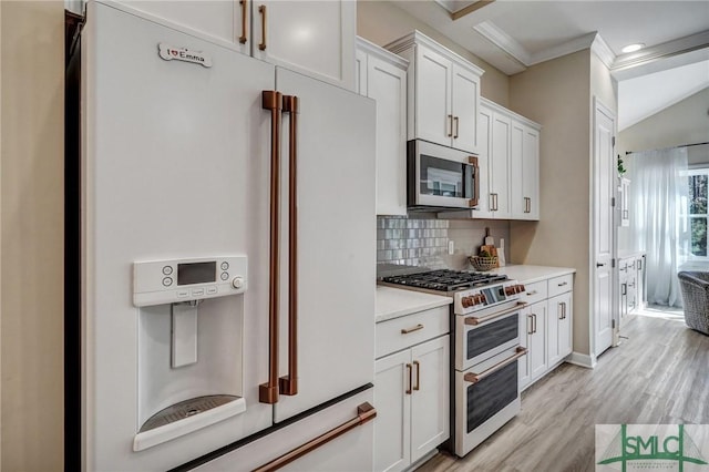 kitchen featuring light wood finished floors, stainless steel appliances, light countertops, white cabinetry, and backsplash