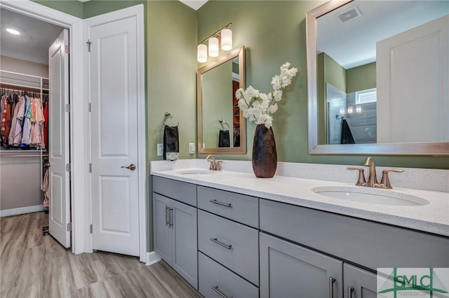 full bathroom with a spacious closet, double vanity, a sink, and visible vents