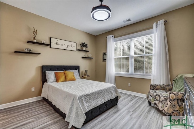 bedroom with light wood finished floors, baseboards, and visible vents