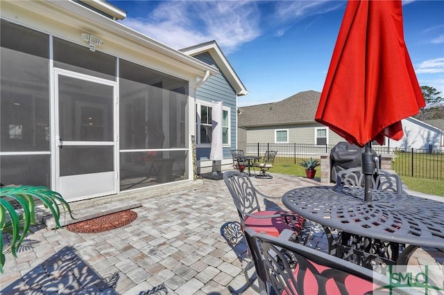 view of patio / terrace featuring outdoor dining space, fence, and a sunroom