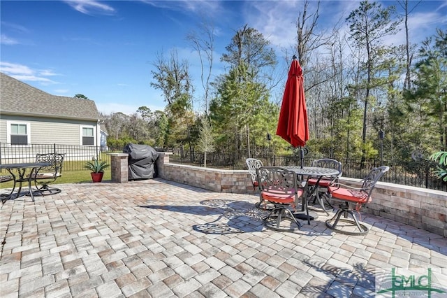 view of patio featuring outdoor dining space, fence, and a grill