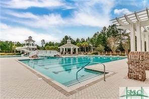 community pool featuring a gazebo, a water slide, a patio area, and a pergola