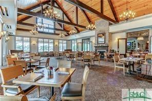 carpeted dining space featuring wooden ceiling, a fireplace, a chandelier, and high vaulted ceiling