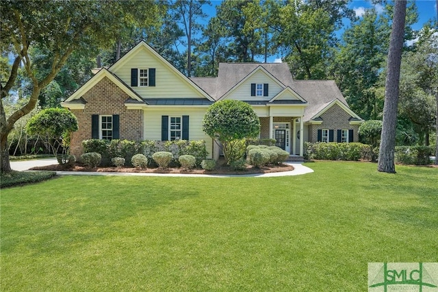 craftsman inspired home featuring a front yard, a standing seam roof, brick siding, and metal roof