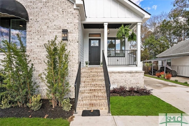 property entrance featuring a porch, board and batten siding, and brick siding