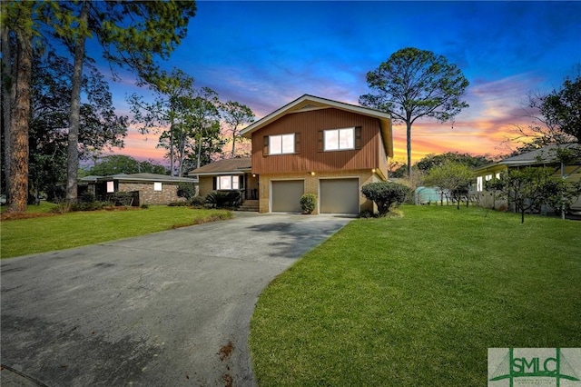 view of front of house featuring a garage, brick siding, driveway, and a yard