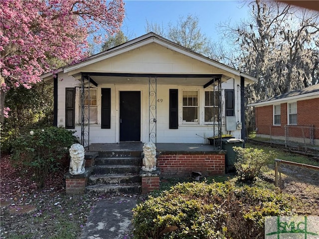 bungalow-style house featuring covered porch and fence