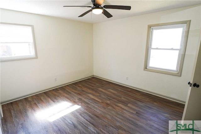 spare room with baseboards, dark wood finished floors, a wealth of natural light, and a ceiling fan