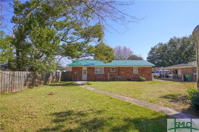 view of front of property with metal roof, a fenced backyard, brick siding, crawl space, and a front yard