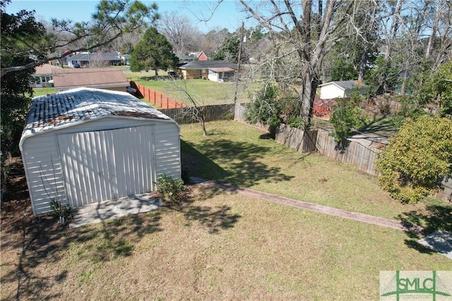 view of yard featuring an outbuilding, a storage unit, a detached garage, and fence