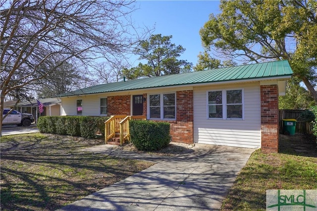 ranch-style house featuring metal roof, concrete driveway, and brick siding