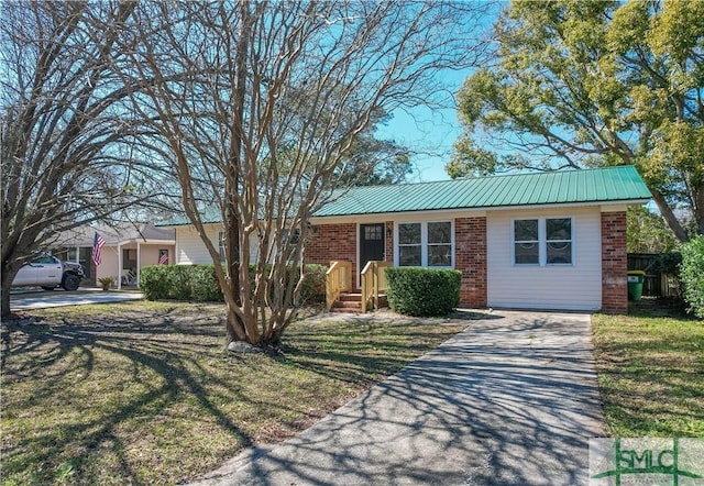 single story home featuring driveway, a front yard, metal roof, and brick siding